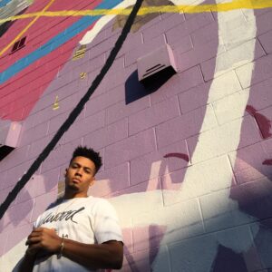 Dynamic portrait of a man posing against a colorful mural wall in Atlanta.